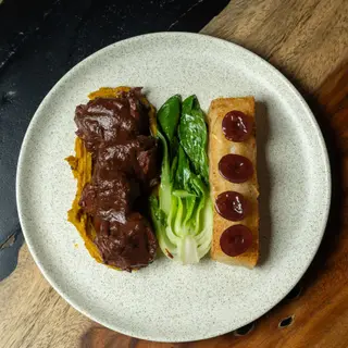 Brisket in Bordelaise sauce with plantain purée, bok choy and a yuca bar topped with grapes